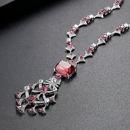 Elegant long crystal and ruby-toned statement necklace worn by a woman in a white dress, ideal for formal luxury fashion and evening events in the UAE.
