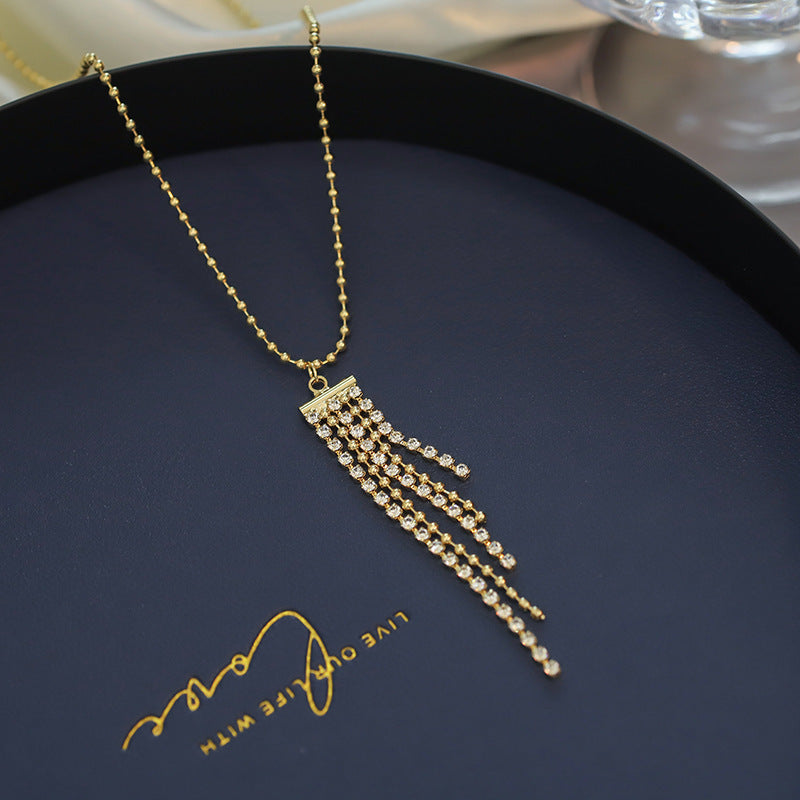 Close-up of an elegant gold floral-shaped geometric necklace with sparkling crystals, displayed on a dark surface for a luxury fashion look.